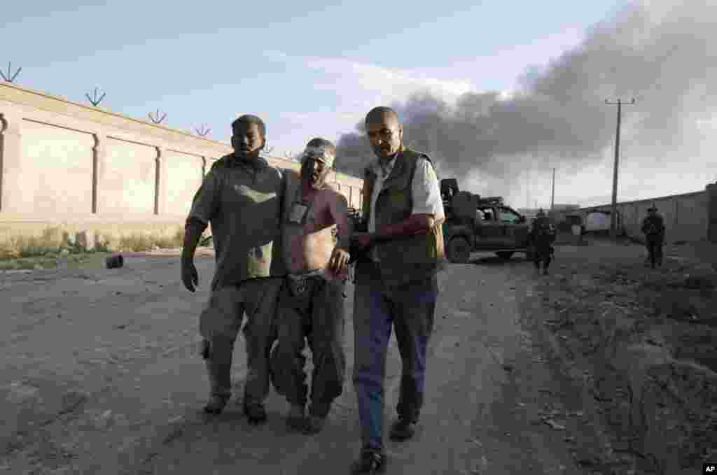 People assist a wounded man after a bombing at the gate to a NATO compound in Kabul, July 2, 2013.
