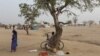 FILE - A man sells tomatoes under a tree at the Minawao refugee camp in Minawao, Cameroon.