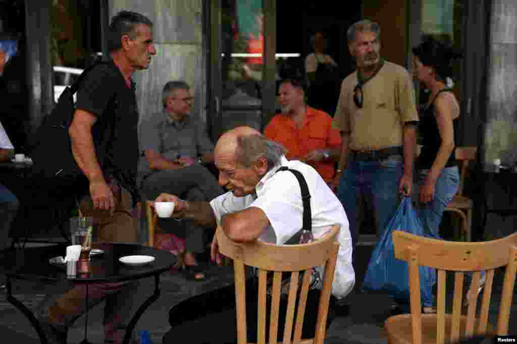 People sit outside a coffee shop in central Athens, July 20, 2015.