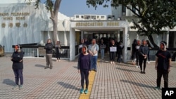 香港电台的员工头戴新闻主播利君雅的面罩在广播大楼外进行静默抗议。（2021年1月28日）