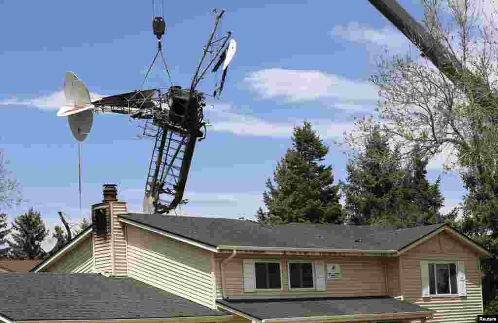 The wreckage of a small plane that crashed into a house is lifted by a crane in Northglenn, Colorado, USA, May 6, 2014. The pilot of a single-engine airplane pulling an advertising banner walked away uninjured after it crashed into an unoccupied home in suburban Denver and set the building on fire, authorities said.