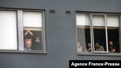 FILE - Asylum seekers gesture to protesters holding a pro-refugee rights rally from their hotel room where they have been detained in Melbourne on June 13, 2020.