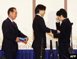 김현희 씨가 2009년 3월 11일 부산에서 일본인 납북 피해자 가족 이즈카 시게오, 이즈카 고이치로 씨와 만나 눈물을 흘리고 있다.