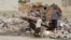 Neighbors collect trash from piles on the street in the hope that government trucks will soon remove the growing stacks of garbage from Mosul, Iraq, Jan. 9, 2017. (H. Murdock/VOA)