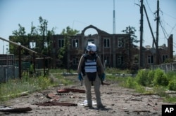 An OSCE monitor checks the territory for mines during a patrol in Shyrokyne, Donetsk region eastern Ukraine, Saturday, July 4, 2015. (AP Photo)