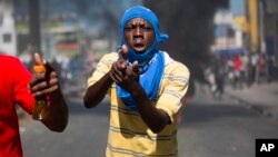 Seorang demonstran menunjuk dengan tangan yang membentuk seperti pistol dalam unjuk rasa menuntut penjelasan mengenai dana bantuan dari Venezuela yang digunakan oleh pemerintah berkuasa, di Port-au-Prince, Haiti, 17 Oktober 2018. 