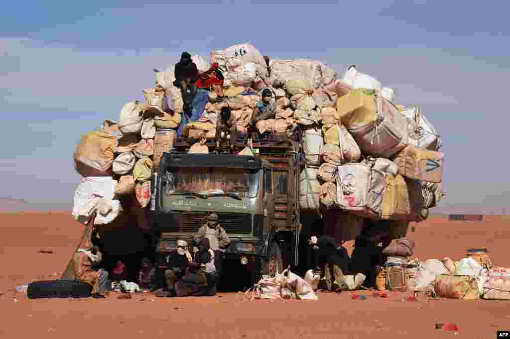 People sit near an overloaded truck in Madama near the border with Libya, Jan. 1, 2015.