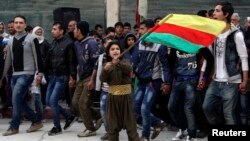 یک پسر کرد پرچم کردهای سوریه را بعد از پیروزی این نیروها در کوبانی در شهر حلب تکان می دهد. 