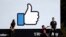 FILE - Visitors take photos in front of the Facebook logo at the company's headquarters, March 28, 2018, in Menlo Park, Calif.