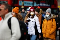 People are pictured wearing protective face masks in London, March 2, 2020.