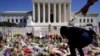 A woman places flowers as people mourn the death of Associate Justice Ruth Bader Ginsburg at the Supreme Court in Washington, Sept. 20, 2020. 