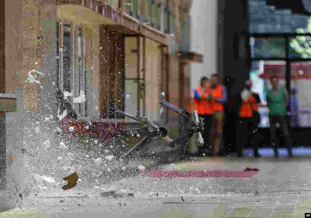 People watch the control detonation of a suspicious package during a bomb alert drill held at the main railway station, Gara de Nord, in Bucharest, Romania.