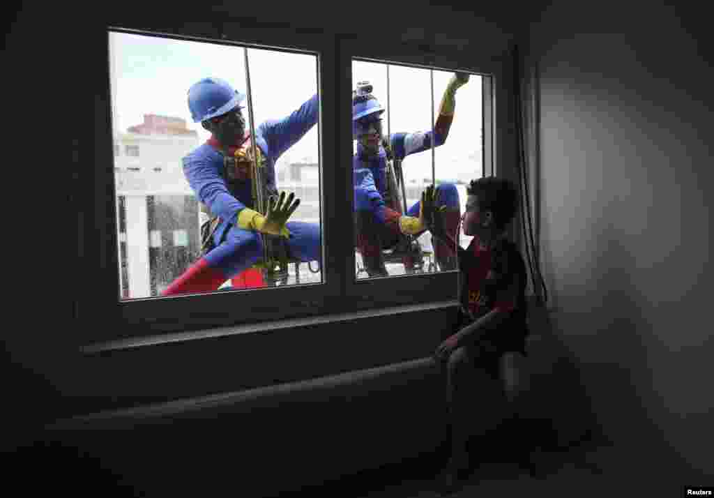 Men dressed as Superman (L) and Captain America smile at patient Caue Rodrigues Silvano, 7, who looks on inside Hospital Infantil Sabara in Sao Paulo, Brazil. The costumed men cleaned the glass facade of the children's hospital, and met with patients.