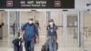 Mike Rustici, left, and Linda Scruggs exit customs after arriving on a flight from Lima, Peru, March 21, 2020, at Miami International Airport in Miami.