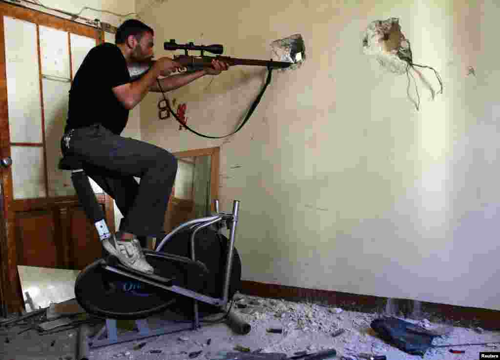 Seorang anggota Pasukan Pembebasan Suriah mengambil posisi dan mengarahkan senapannya ke Justice Palace, yang dikuasai oleh pasukan setia Presiden Suriah Bashar al-Assad, di Aleppo. 