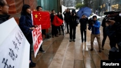 在加拿大不列颠哥伦比亚省一家正在审理孟晚舟案的法院外手举中国国旗和标语牌的孟晚舟支持者。（2018年12月11日）