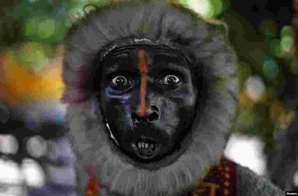 Seorang pengemis di New Delhi, India meminta-minta dengan memakai kostum seperti seekor monyet.