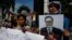 A Cambodian opposition party supporter, right, holds a portrait photo of an opposition senator Hong Sok Hour during a protest in front of the Phnom Penh Municipal Court, in Phnom Penh, Cambodia, Saturday, Aug. 15, 2015. 