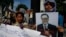 A Cambodian opposition party supporter, right, holds a portrait photo of an opposition senator Hong Sok Hour during a protest in front of the Phnom Penh Municipal Court, in Phnom Penh, Cambodia, Saturday, Aug. 15, 2015. 