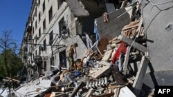 به دنبال انفجار بمب در مرکز شهر، امدادگران آوارها را در محل یک ساختمان مسکونی بازرسی می‌کنند. خارکیف، اوکراین، دوم تیر ۱۴۰۳