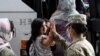 FILE - In this Aug. 30, 2021, photo, Army Pfc. Kimberly Hernandez gives a high-five to a girl evacuated from Kabul, before boarding a bus after they arrived at Washington Dulles International Airport.