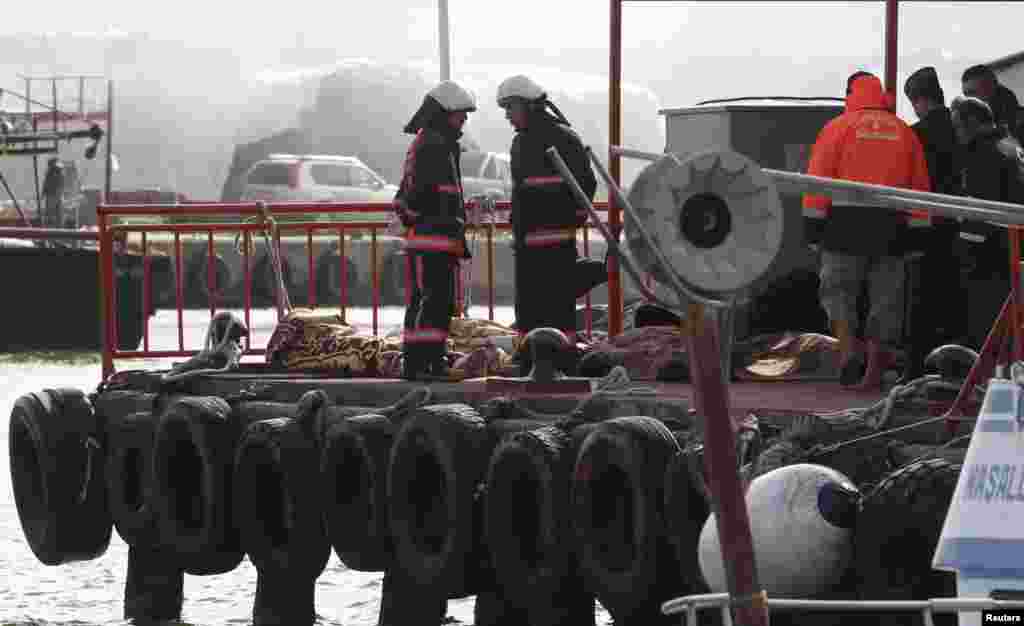 Rescue workers stand next to bodies retrieved from the sea after a boat sank in the Bosphorus strait, in the Black Sea village of Garipce, near Istanbul, Nov. 3, 2014. 