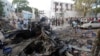 Rescue workers stand near the wreckage of vehicles in Mogadishu, Somalia, Oct 29, 2017, after a car bomb was detonated. 