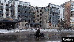 A woman walks past a building damaged by a Russian military strike in the town of Pokrovsk