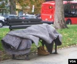 Seorang tunawisma tidur berbalut selimut di bangku taman di pusat kota Washington DC. Setiap tahun sekitar 700 tunawisma di AS tewas akibat hipotermia.