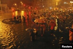 Regu penyelamat dan penduduk setempat berupaya menolong sebuah mobil yang terjebak banjir di Guangqumen, Beijing, (21/7).