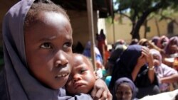 Msichana wa kisomali akimbeba dadake wakisubiri kupewa chakula kutoka WFP mjini Mogadishu