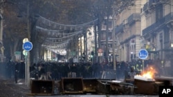 Los manifestantes están parados detrás de un cubo en llamas durante los enfrentamientos, el sábado 8 de diciembre de 2018 en Marsella, en el sur de Francia.