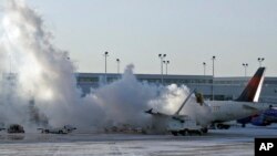 Sebuah pesawat maskapai Delta di bandara Chicago harus dibersihkan dari lapisan es (6/1). Beberapa maskapai membatalkan penerbangan di AS akibat suhu udara yang membeku.