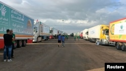 2023年10月17日，在埃及拉法，载有人道主义援助物资的卡车等待拉法过境点重新开放，以便在以色列和哈马斯之间持续不断的冲突中进入加沙。（路透社照片）
