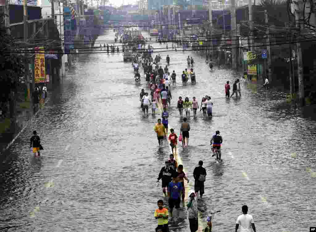 People walk on a flooded street in suburban Pasig City, east of Manila, Philippines, August 9, 2012.