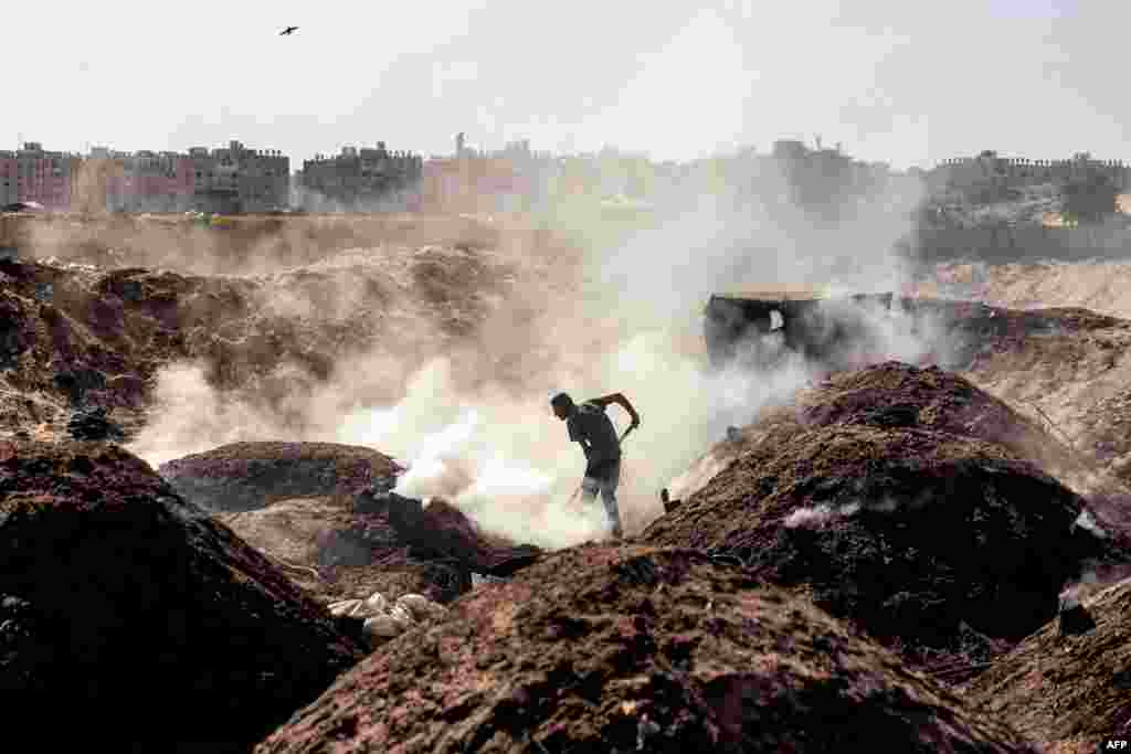 A man shovels at a charcoal production site in Khan Yunis in the southern Gaza Strip, amid the ongoing war in the Palestinian territory between Israel and Hamas.