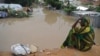 A woman living at a camp for the internally displaced sits on high ground above a flooded street on May 20, 2018 in Mogadishu after temporary shelters were inundated in Somalia's capital following heavy overnight rainfall. 