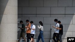 北京写字楼前年轻人边走路边看手机。