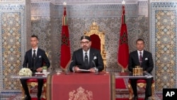 In this photo provided by the Moroccan News Agency (MAP), Morocco's King Mohammed VI, center, accompanied by his son Crown Prince Moulay Hassan, left, and brother Prince Moulay Rashid addresses the Nation in a speech aired on TV, at the Royal Palace.