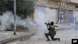 Seorang tentara Libya menembakkan senjatanya dalam bentrokan dengan milisi Islamis di Benghazi (30/10). Milisi Islamis masih menguasai sebagian besar wilayah di Libya.