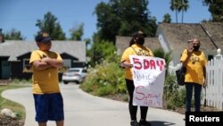 Maria Osorio, 51, holds a flag as she protests with others outside the home of California Senate Majority Leader Bob Hertzberg to urge legislators to pass AB 1436, which would prohibit landlords from evicting tenants, July 17, 2020.
