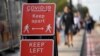 FILE - Pedestrians walk near public health signs in London, Britain, Sept. 11, 2020. 