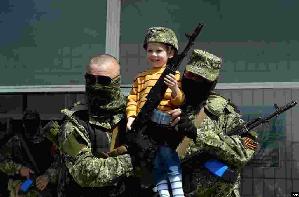 Pro-Russian armed men in military fatigues pose for a photograph with a child as they stand guard outside a regional administration building seized overnight by pro-Russian separatists, in the eastern Ukrainian city of Kostyantynivka.