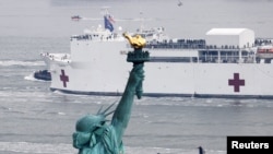 Kapal Rumah Sakit USNS Comfort melintas di depan Patung Liberty saat memasuki Pelabuhan New York di tengah wabah virus corona (COVID-19) di Kota New York, 30 Maret 2020. (Foto: Reuters)