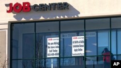 FILE - A man walks past signs posted at an employment agency, in Manchester, New Hampshire, March 2, 2021. 