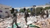 Somali soldiers walk near a destroyed building after a car bomb in Mogadishu, May 14, 2019.