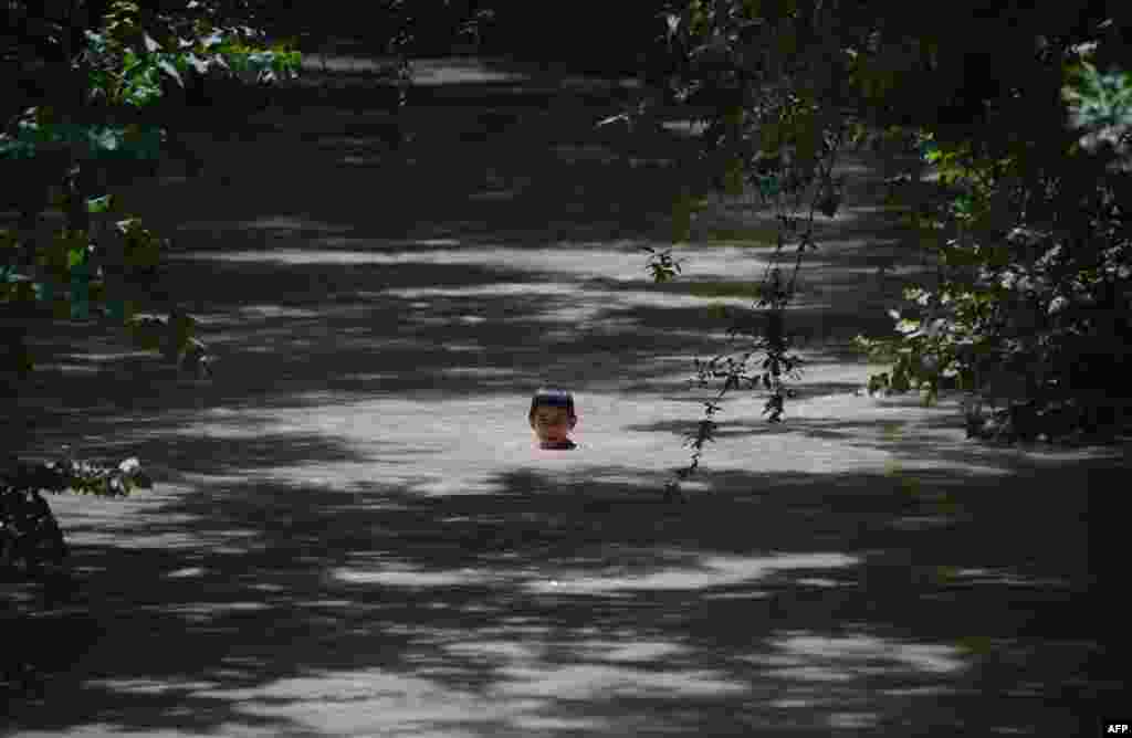 ក្មេង​ប្រុស​ជនជាតិ​អាហ្វហ្គានីស្ថាន​ម្នាក់​ហែលទឹក​ក្នុង​ប្រឡាយទឹក​ភក់​នៅជាយក្រុង​ Mazar-i-Sharif។