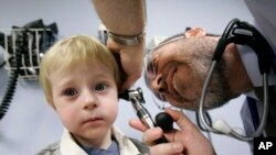 FILE - A child has his ear examined by a doctor at Children's Hospital of Pittsburgh, in Pittsburgh, Nov. 20, 2006.