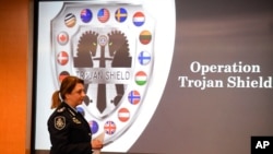 Commander Xenia Cotter, from the Australian Federal Police, walks past an Operation Trojan Shield logo during a news conference, in San Diego, June 8, 2021. 