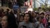 Thai supporters stand beside an electoral campaign poster of prime minister Yingluck Shinawatra (top) as they cheer on anti-government protesters marching along the streets in downtown Bangkok, Jan. 30, 2014. 